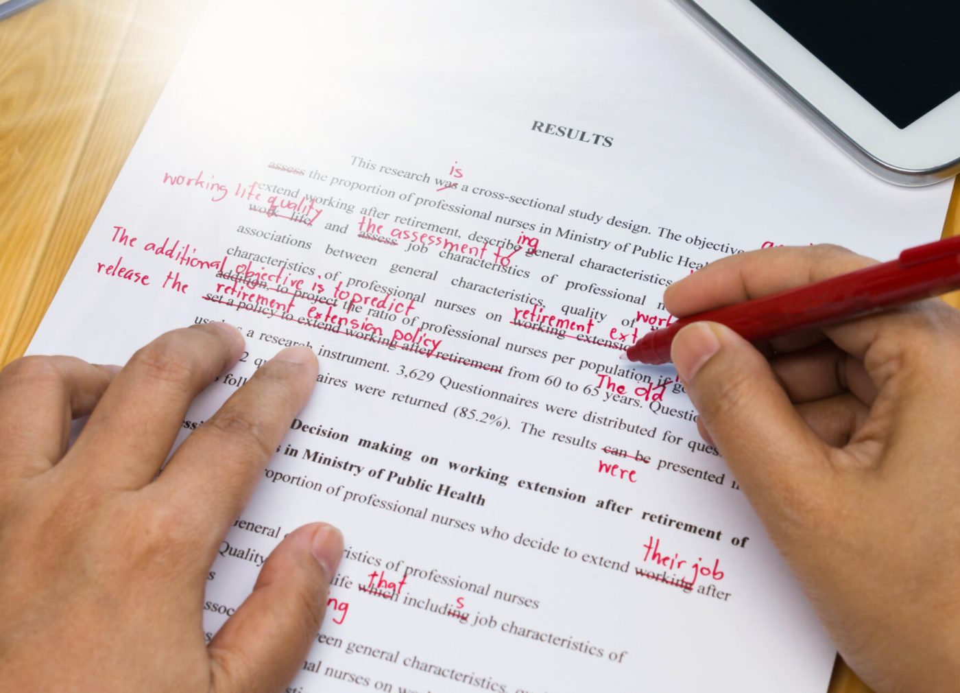 Hand,Holding,Red,Pen,Over,Proofreading,Text,On,Table